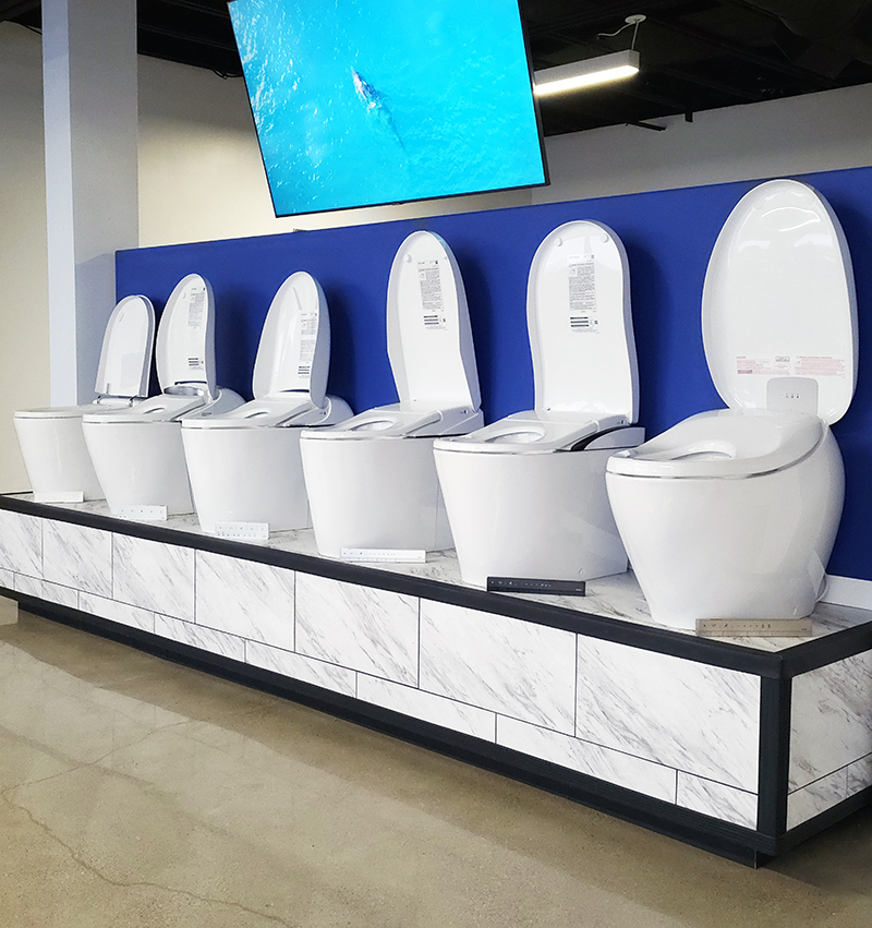 A photograph of the main bidet display in the Many Bidets showroom featuring integrated bidet toilets